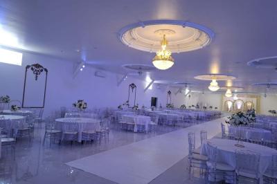 Bâtiment moderne avec façade noire, terrasse aménagée, murs végétalisés et sculptures, sous un ciel nuageux.