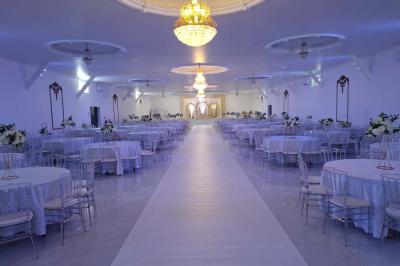 Bâtiment moderne avec façade noire, terrasse aménagée, murs végétalisés et sculptures, sous un ciel nuageux.