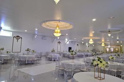 Bâtiment moderne avec façade noire, terrasse aménagée, murs végétalisés et sculptures, sous un ciel nuageux.