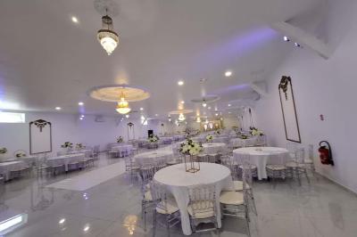 Bâtiment moderne avec façade noire, terrasse aménagée, murs végétalisés et sculptures, sous un ciel nuageux.