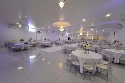 Bâtiment moderne avec façade noire, terrasse aménagée, murs végétalisés et sculptures, sous un ciel nuageux.