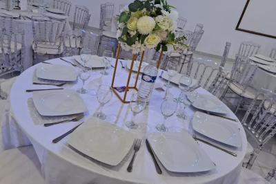 Bâtiment moderne avec façade noire, terrasse aménagée, murs végétalisés et sculptures, sous un ciel nuageux.