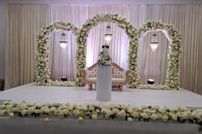 Bâtiment moderne avec façade noire, terrasse aménagée, murs végétalisés et sculptures, sous un ciel nuageux.