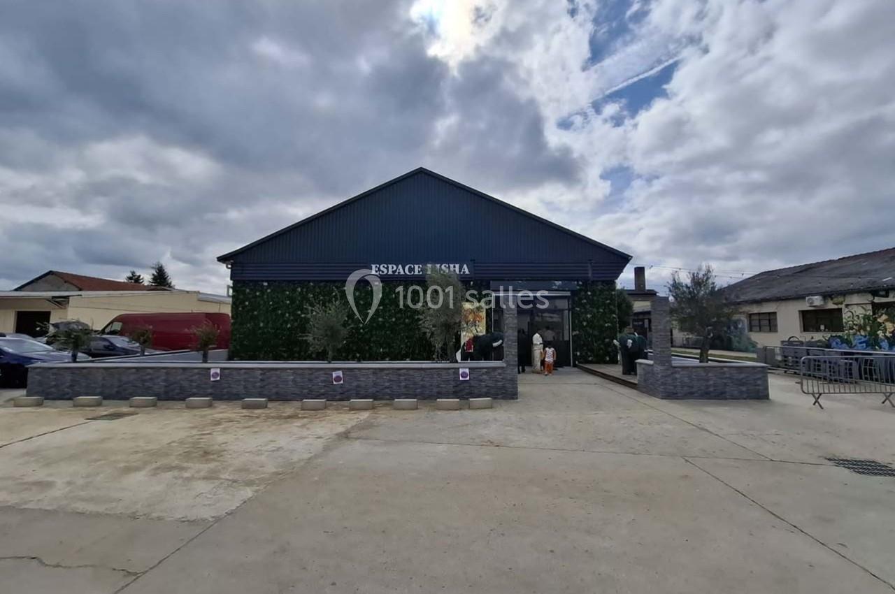 Façade d'un bâtiment moderne avec un mur végétalisé, une enseigne ’Espace Nisha’ et un ciel nuageux en arrière-plan.