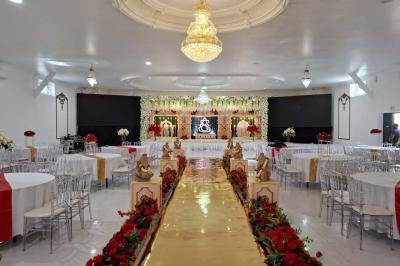 Bâtiment moderne avec façade noire, terrasse aménagée, murs végétalisés et sculptures, sous un ciel nuageux.