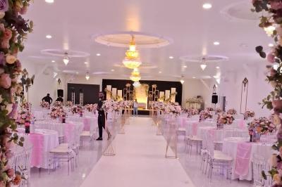 Bâtiment moderne avec façade noire, terrasse aménagée, murs végétalisés et sculptures, sous un ciel nuageux.