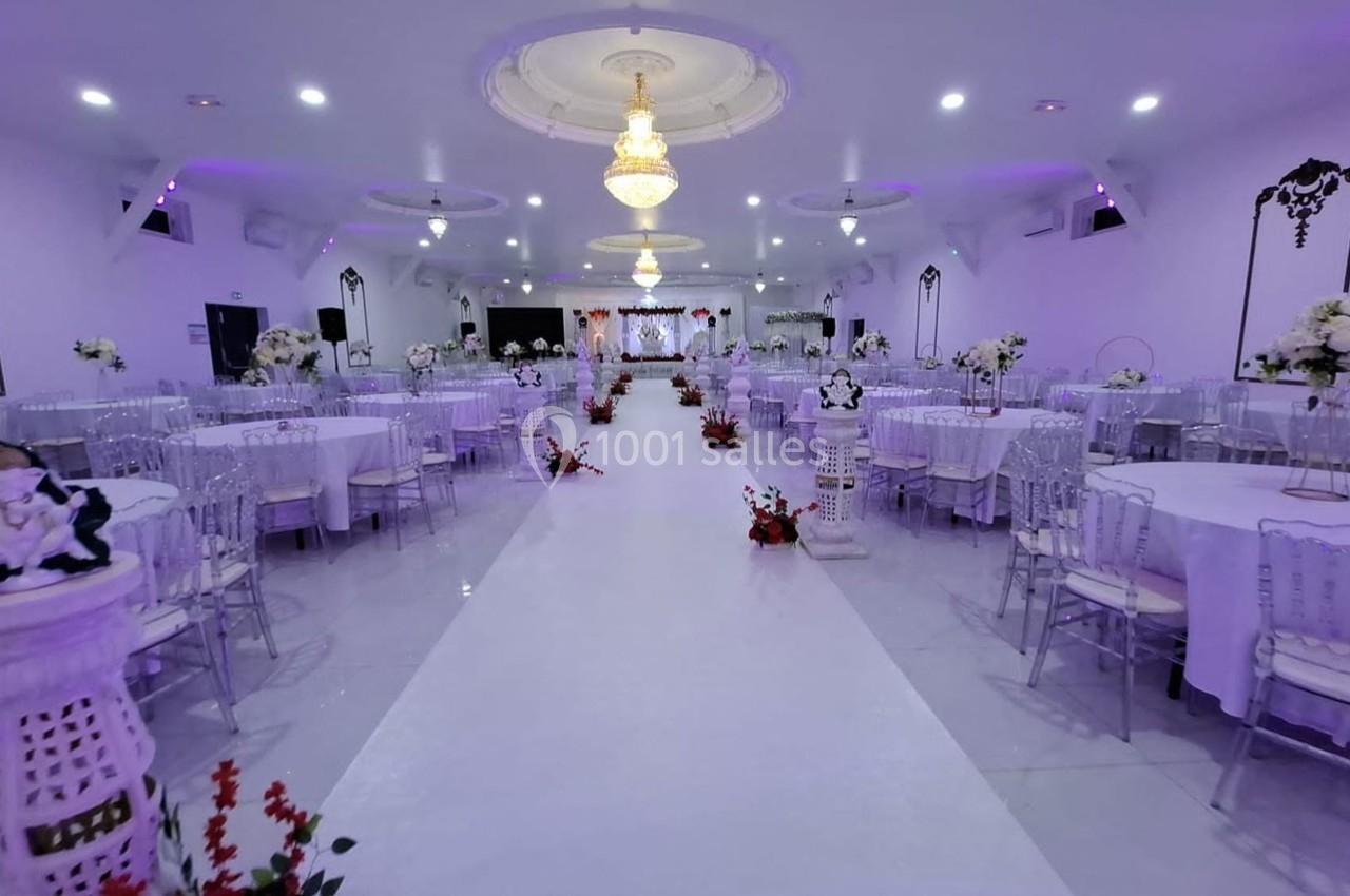 Salle de réception décorée avec des tables rondes, des chaises transparentes et des arrangements floraux sous un éclairage…