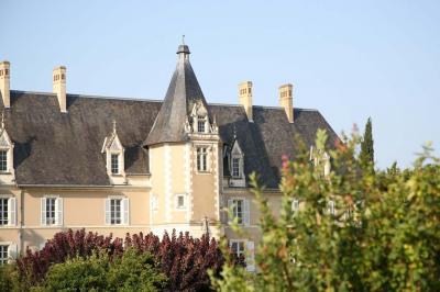 Façade d'un château avec une tour centrale et des fenêtres, entouré de végétation.