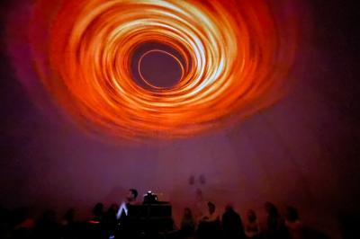 Dôme gonflable noir avec motif de galaxie, utilisé pour des projections, installé dans un gymnase.