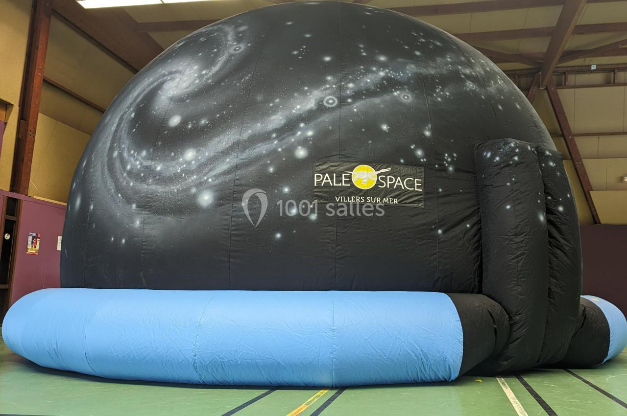 Dôme gonflable noir avec motif de galaxie, utilisé pour des projections, installé dans un gymnase.