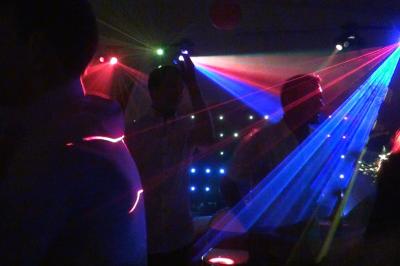 Personnes dansant dans une ambiance de fête avec des lumières colorées et des faisceaux laser.