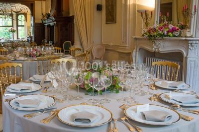 Un petit pont en bois traverse un ruisseau entouré de verdure et de fleurs dans un paysage forestier.