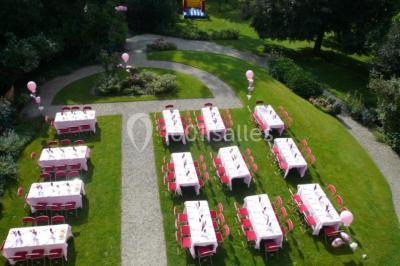 Un petit pont en bois traverse un ruisseau entouré de verdure et de fleurs dans un paysage forestier.