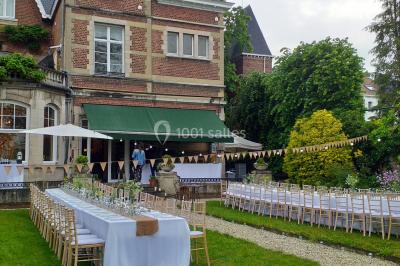 Un petit pont en bois traverse un ruisseau entouré de verdure et de fleurs dans un paysage forestier.