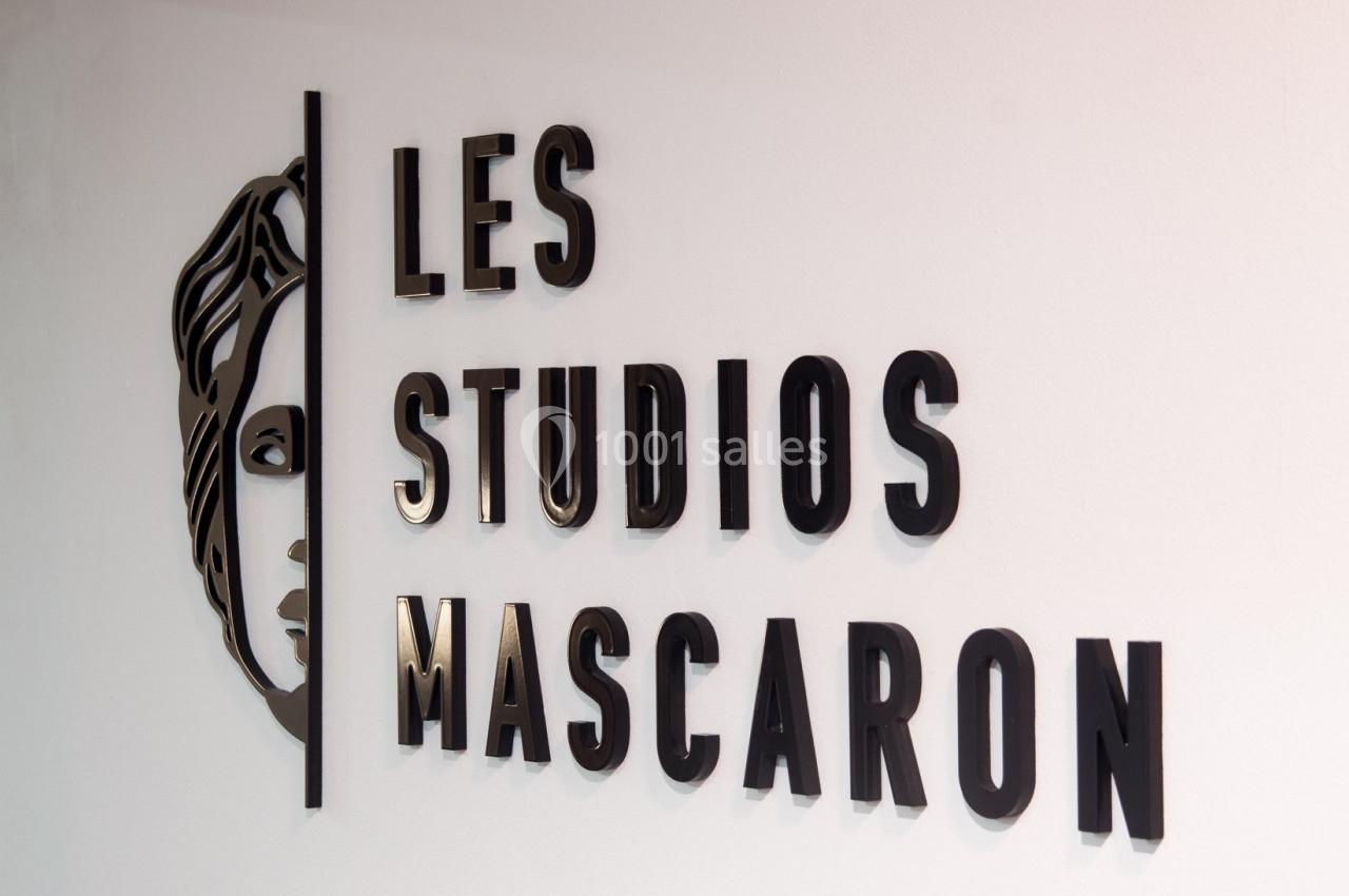 Logo mural des ’Studios Mascaron’ avec un visage stylisé à gauche, en lettres noires sur fond blanc.