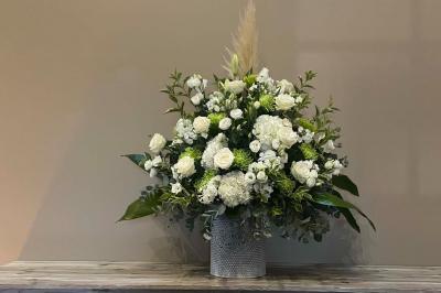 Bâtiment en pierre avec toit en pente, tables et chaises disposées sur une terrasse et une pelouse au premier plan.