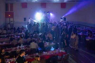Grande salle en bois avec charpente apparente, éclairages rouges, matériel de sonorisation et espace vide au centre.