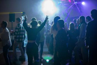 Grande salle en bois avec charpente apparente, éclairages rouges, matériel de sonorisation et espace vide au centre.