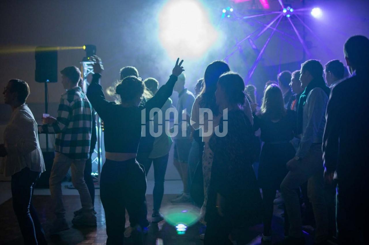 Groupe de personnes dansant sous des lumières colorées dans une ambiance festive.