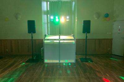 Grande salle en bois avec charpente apparente, éclairages rouges, matériel de sonorisation et espace vide au centre.