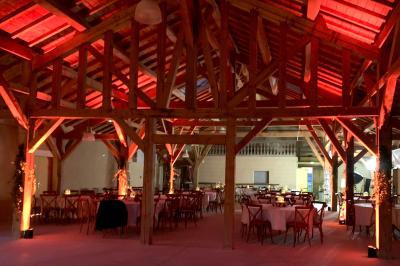 Salle en bois avec charpente apparente, équipée de matériel de sonorisation et d'éclairage pour un événement.