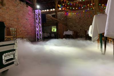 Salle en bois avec charpente apparente, équipée de matériel de sonorisation et d'éclairage pour un événement.