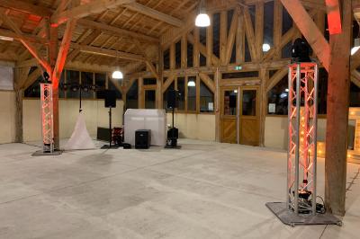 Salle en bois avec charpente apparente, équipée de matériel de sonorisation et d'éclairage pour un événement.