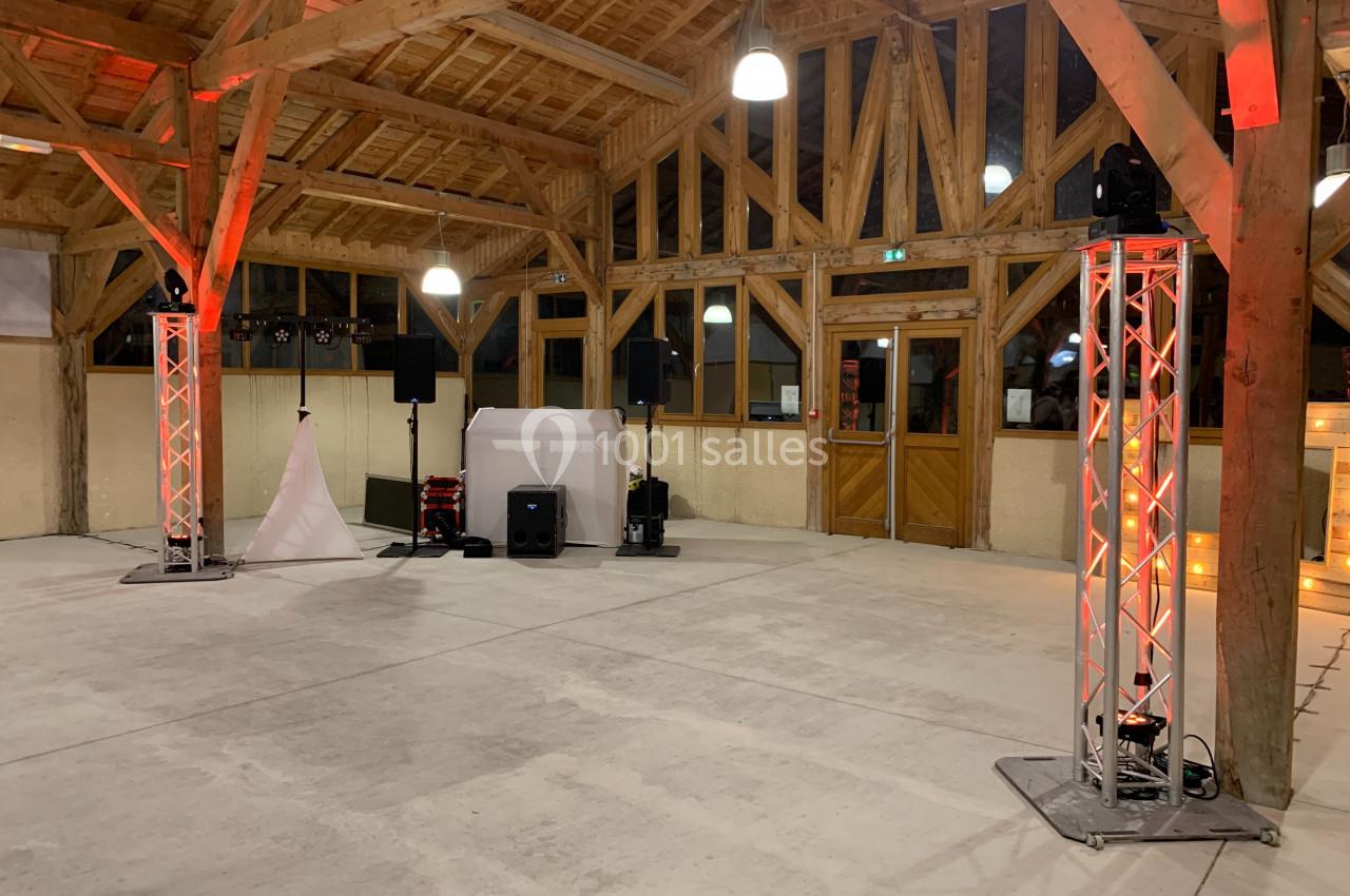 Salle en bois avec charpente apparente, équipée de matériel de sonorisation et d'éclairage pour un événement.