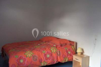 Un jardin verdoyant avec des arbres, de l'herbe fraîchement tondue, un banc en pierre et une clôture en arrière-plan.