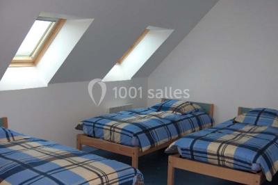 Un jardin verdoyant avec des arbres, de l'herbe fraîchement tondue, un banc en pierre et une clôture en arrière-plan.