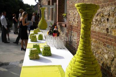 Un jardin verdoyant avec des arbres, de l'herbe fraîchement tondue, un banc en pierre et une clôture en arrière-plan.