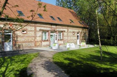 Un jardin verdoyant avec des arbres, de l'herbe fraîchement tondue, un banc en pierre et une clôture en arrière-plan.