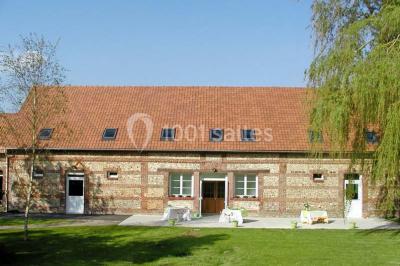 Un jardin verdoyant avec des arbres, de l'herbe fraîchement tondue, un banc en pierre et une clôture en arrière-plan.
