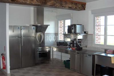 Un jardin verdoyant avec des arbres, de l'herbe fraîchement tondue, un banc en pierre et une clôture en arrière-plan.