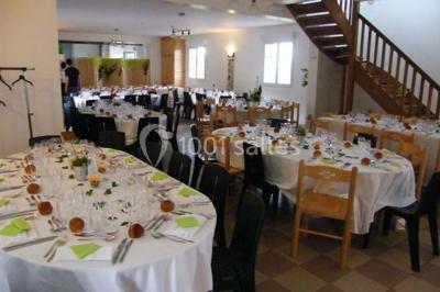 Un jardin verdoyant avec des arbres, de l'herbe fraîchement tondue, un banc en pierre et une clôture en arrière-plan.