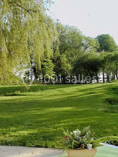 Un jardin verdoyant avec pelouse, arbres en arrière-plan et un bouquet de fleurs au premier plan.