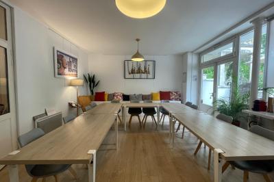 Terrasse en pierre avec mobilier de jardin, entourée de plantes en pots, donnant sur des immeubles en briques.