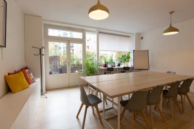 Terrasse en pierre avec mobilier de jardin, entourée de plantes en pots, donnant sur des immeubles en briques.