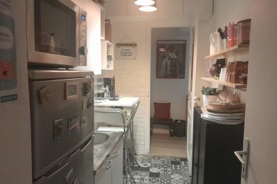 Terrasse en pierre avec mobilier de jardin, entourée de plantes en pots, donnant sur des immeubles en briques.