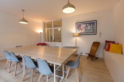 Terrasse en pierre avec mobilier de jardin, entourée de plantes en pots, donnant sur des immeubles en briques.