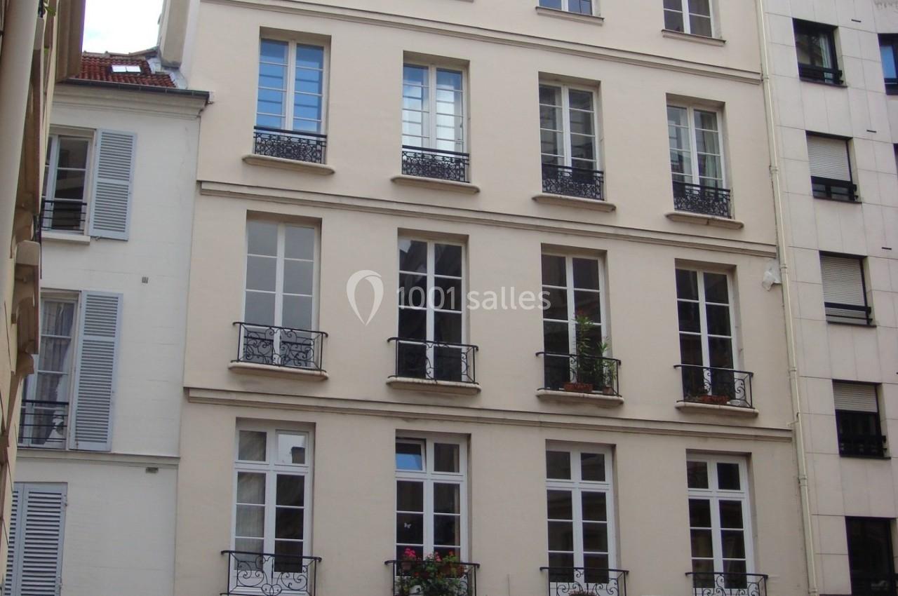 Façade d'un immeuble résidentiel parisien de plusieurs étages avec fenêtres et balcons en fer forgé.