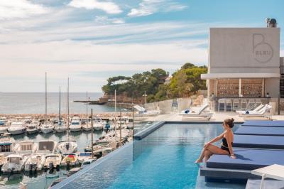 Table dressée pour deux avec vue sur un port de plaisance, des voiliers et la mer sous un ciel dégagé.