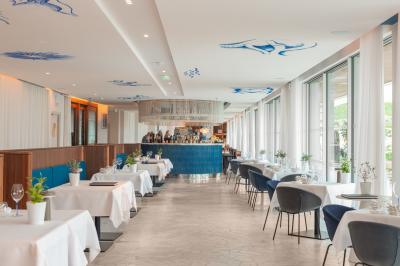 Table dressée pour deux avec vue sur un port de plaisance, des voiliers et la mer sous un ciel dégagé.