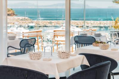 Table dressée pour deux avec vue sur un port de plaisance, des voiliers et la mer sous un ciel dégagé.