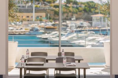 Table dressée pour deux avec vue sur un port de plaisance, des voiliers et la mer sous un ciel dégagé.