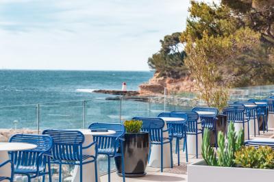 Table dressée pour deux avec vue sur un port de plaisance, des voiliers et la mer sous un ciel dégagé.