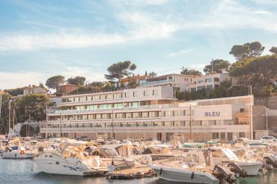 Table dressée pour deux avec vue sur un port de plaisance, des voiliers et la mer sous un ciel dégagé.