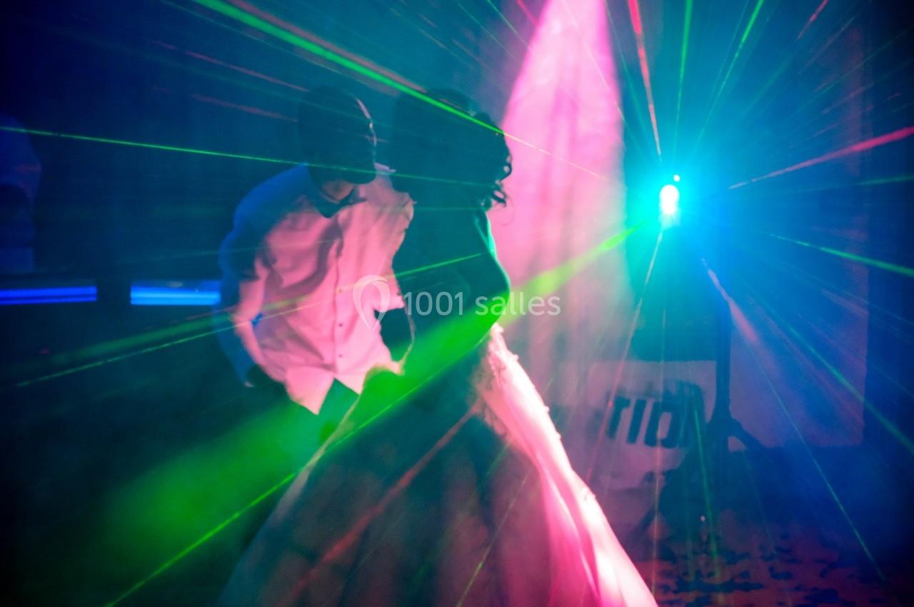 Un couple danse sous des lumières colorées et des faisceaux laser dans une ambiance festive.