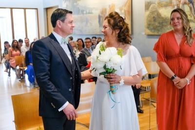 Un couple danse ensemble dans une salle décorée de ballons, entouré de quelques invités en arrière-plan.