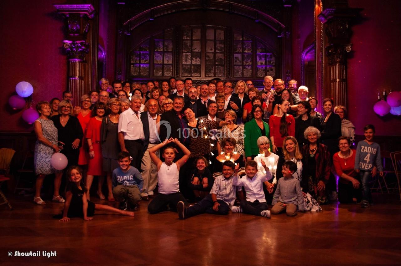 Groupe de personnes posant dans une grande salle décorée avec des lumières et des ballons.
